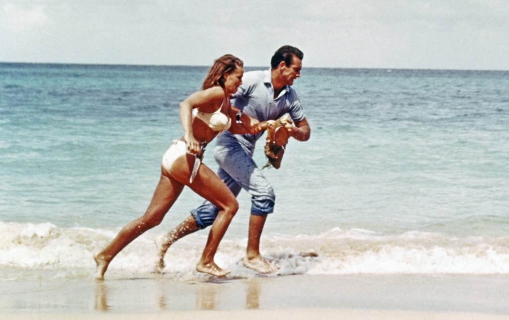 James Bond mit Bond-Girl am Strand.