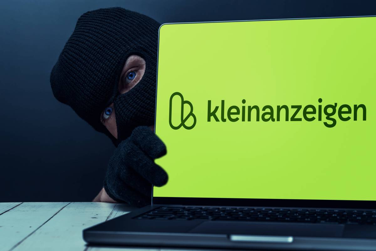 Ein Mann mit Skimaske versteckt sich hinter einem Notebook, auf dem das Verkaufsportal Kleinanzeigen geöffnet ist.