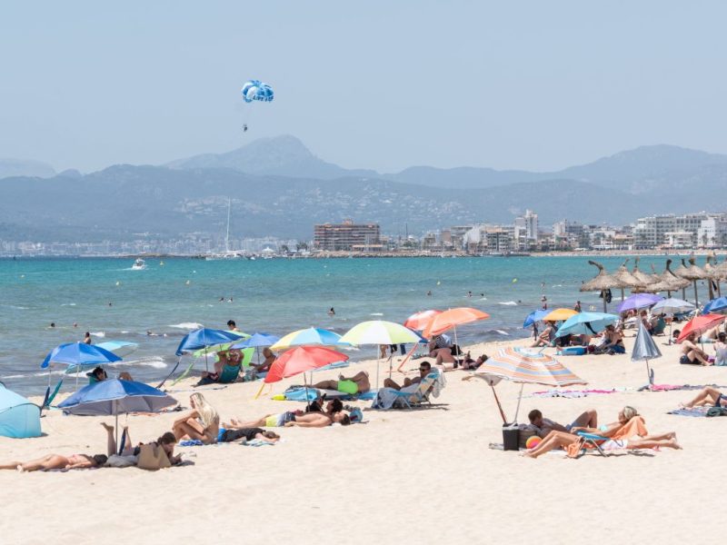 Menschen liegen an einem Strand auf Mallorca.
