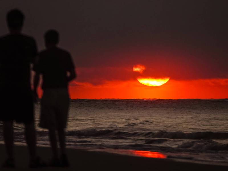 Zwei Männer am Strand bei Sonnenuntergang.