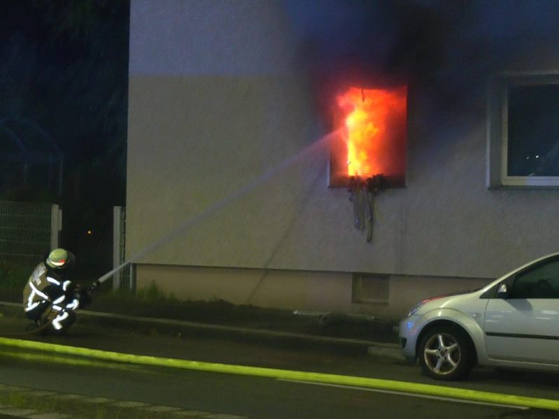 Wohnungsbrand in Essen: Ein Feuerwehrmann löscht von außen durch das zerstörte Fenster.
