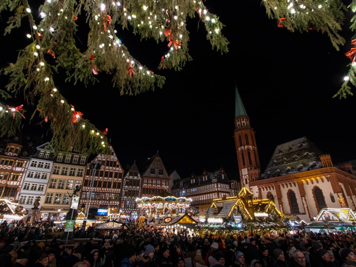 Ausblick auf großen Weihnachtsmarkt hinter Tannenzweigen.