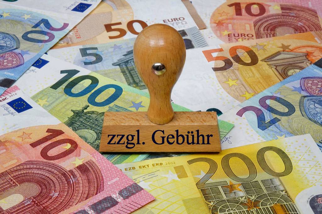 Alt-Text: Nahaufnahme von Geldscheinen und einem Stempel mit der Aufschrift "Gebühren".