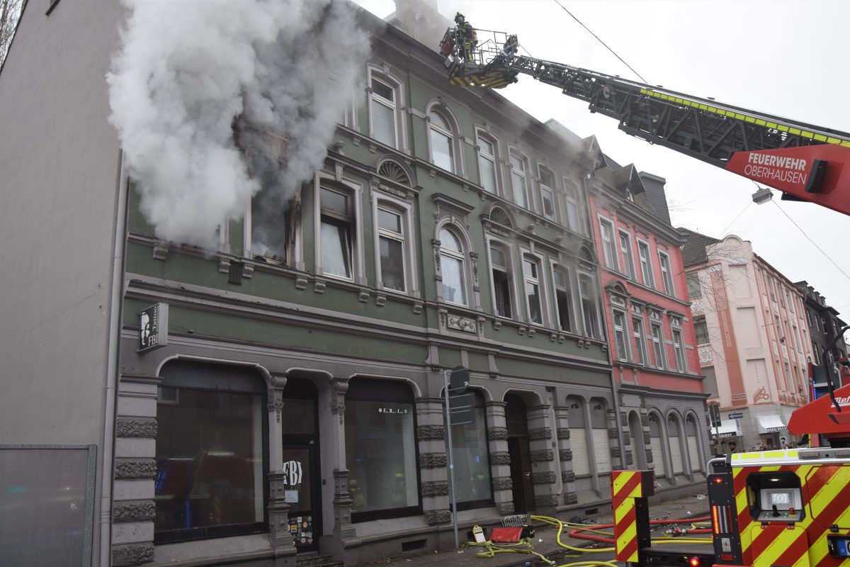 Dichter Rauch quillt aus der brennenden Wohnung in Oberhausen. Per Drehleiter rettet die Feuerwehr eingeschlossene Bewohner aus den anderen Wohnungen.